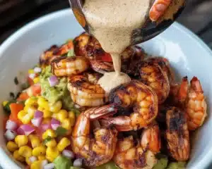 Grilled shrimp bowl featuring avocado, corn salsa, and creamy garlic sauce.
