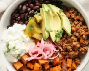 Colorful sweet potato taco bowls with toppings like avocado and beans.