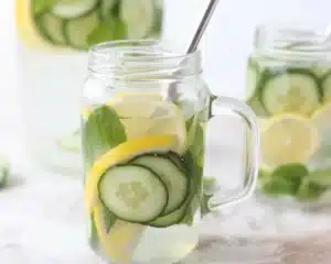 A refreshing pitcher of Lemon Mint and Cucumber Water with slices of lemon and cucumber.