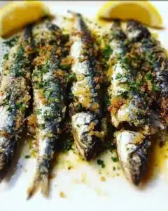 Herb-crusted roasted sardines with Mediterranean garlic served on a plate.