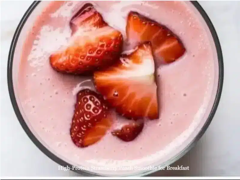 High-protein strawberry peach smoothie in a glass with fresh fruits beside it