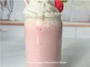Protein-packed strawberry shake in a glass with strawberries on the side