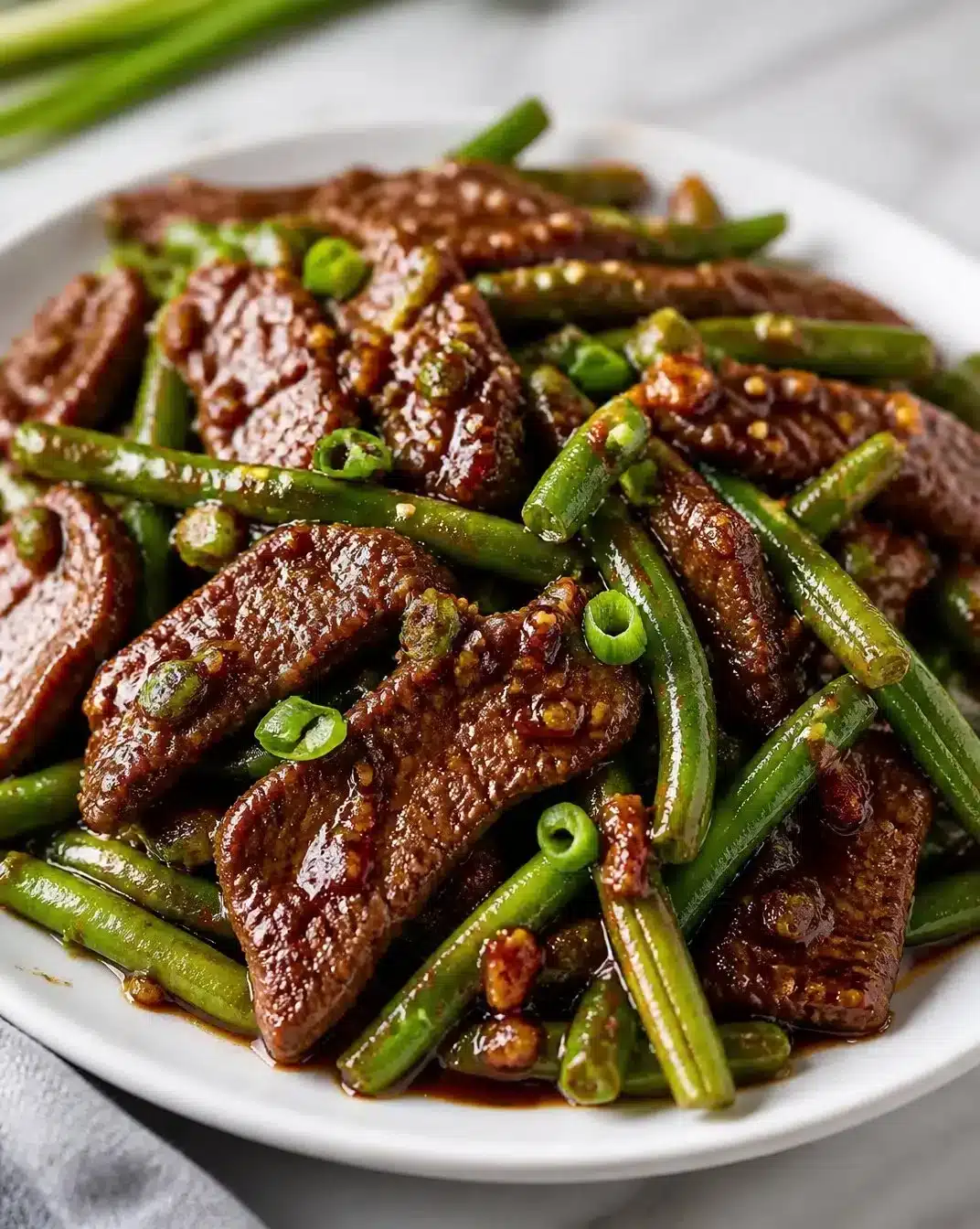 Garlic-Infused Griddle Beef with Green Beans 1 Garlic-infused griddle beef served with green beans on a plate.