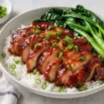 Sliced char siu chicken served over rice with greens and scallions